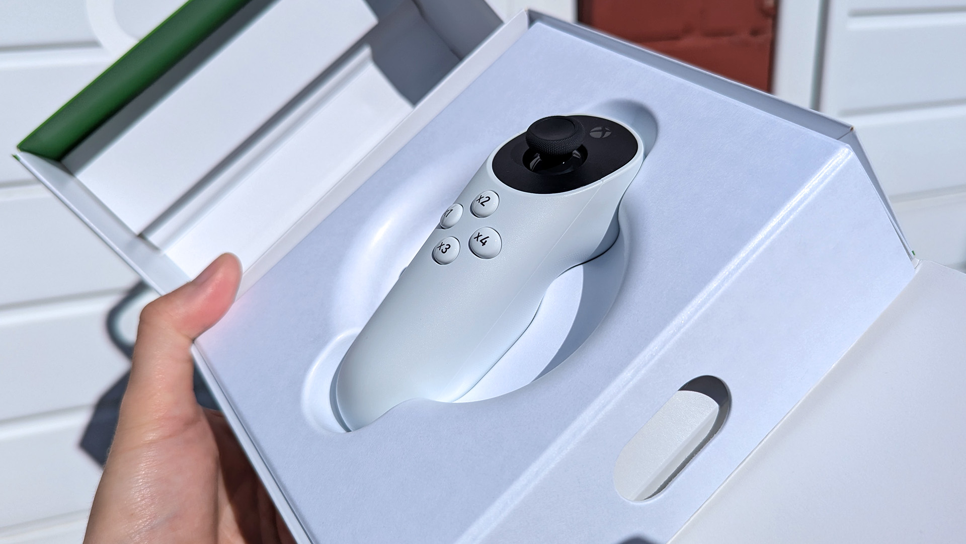 Адаптивный джойстик Xbox в руке, в открытой розничной коробке