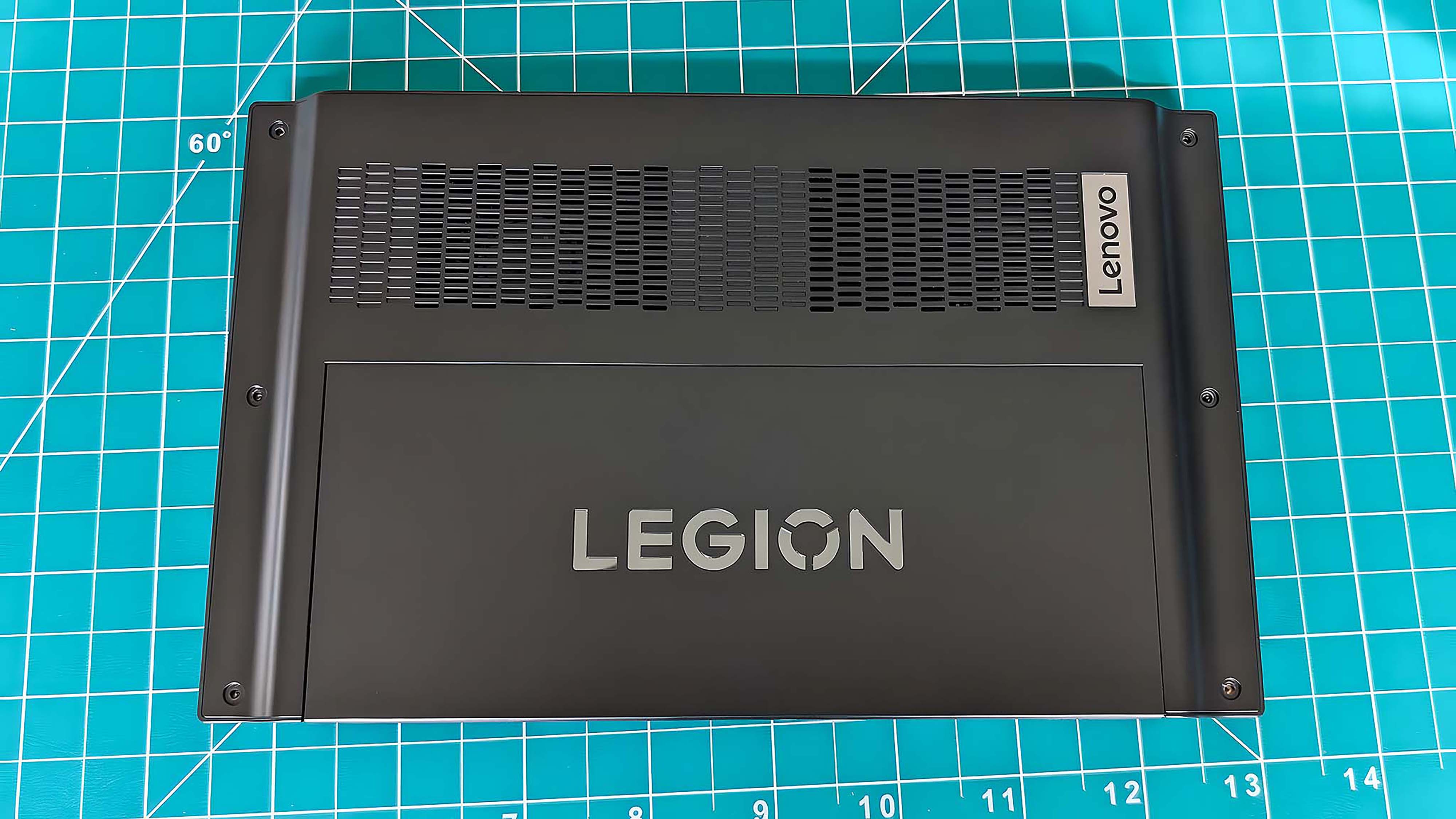 Задняя сторона Lenovo Legion Go, лежащего экраном вниз на зеленом коврике.