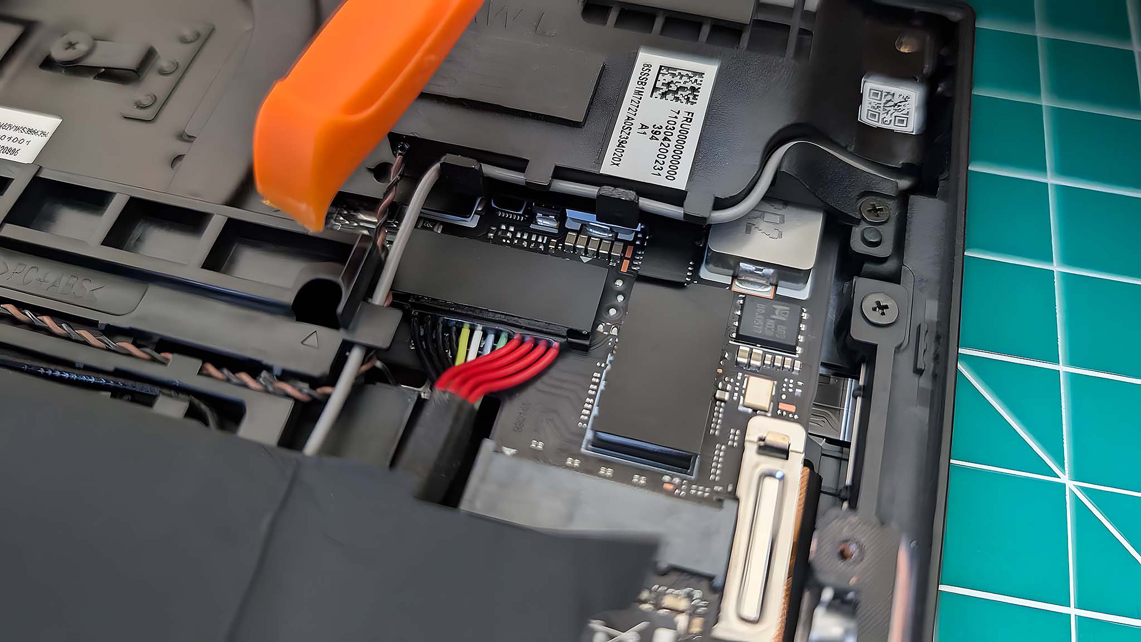 Инструмент для вскрытия нависает над кабелями аккумулятора Lenovo Legion Go.