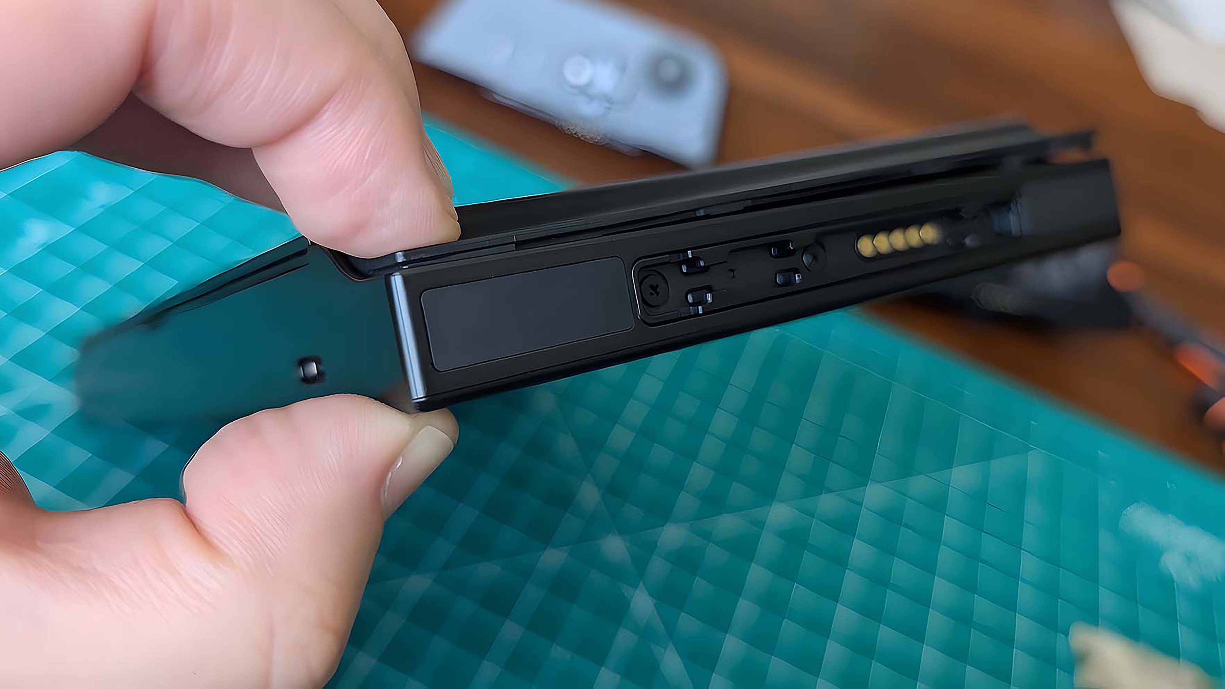 Палец и большой палец сжимают закрытый корпус Lenovo Legion Go.