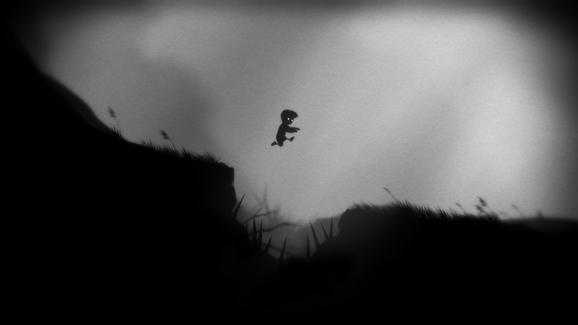 A boy jumps over a spike pit in Limbo