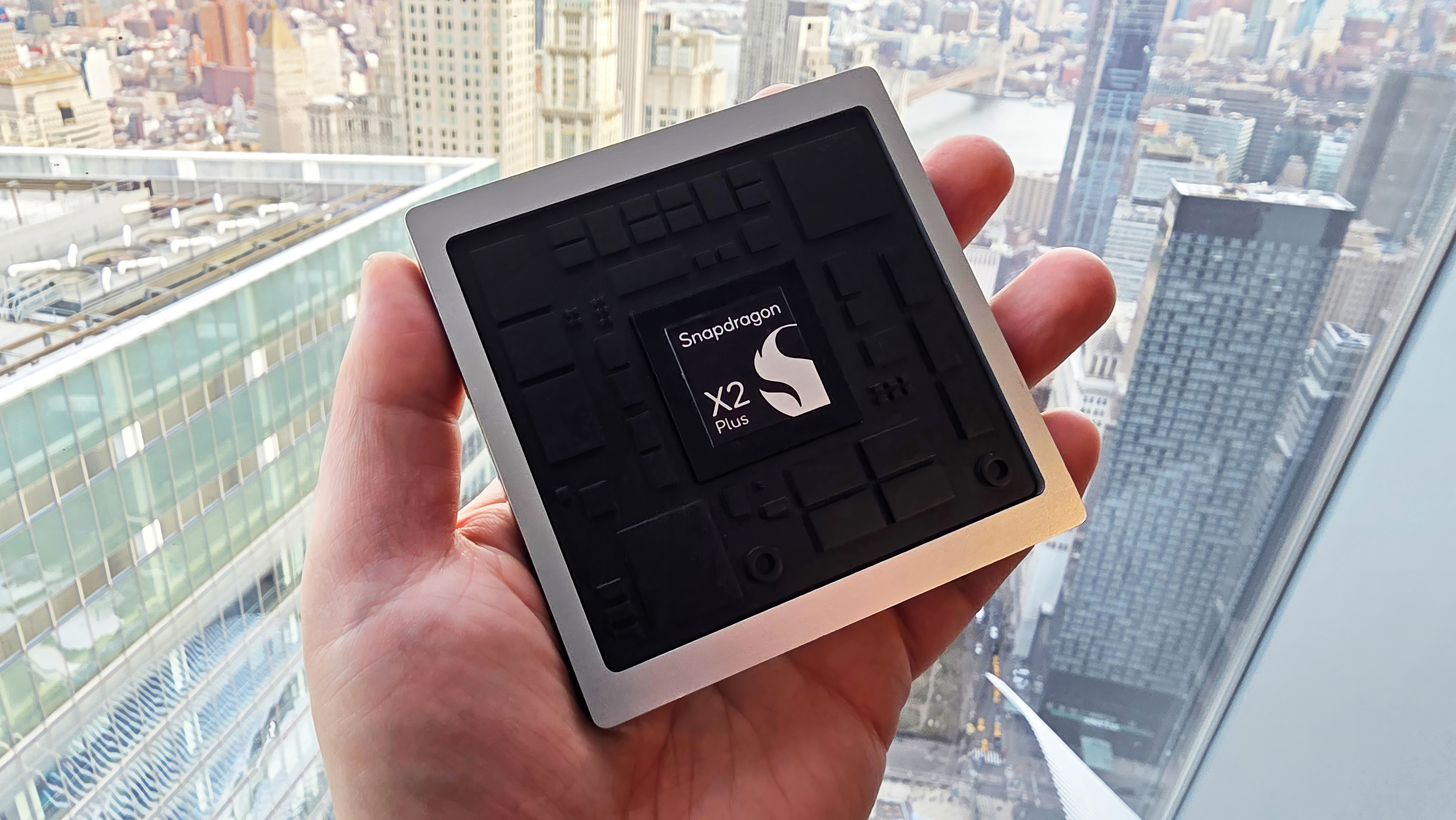 Рекламный макет нового процессора Qualcomm X2 Plus, держащегося за окно.