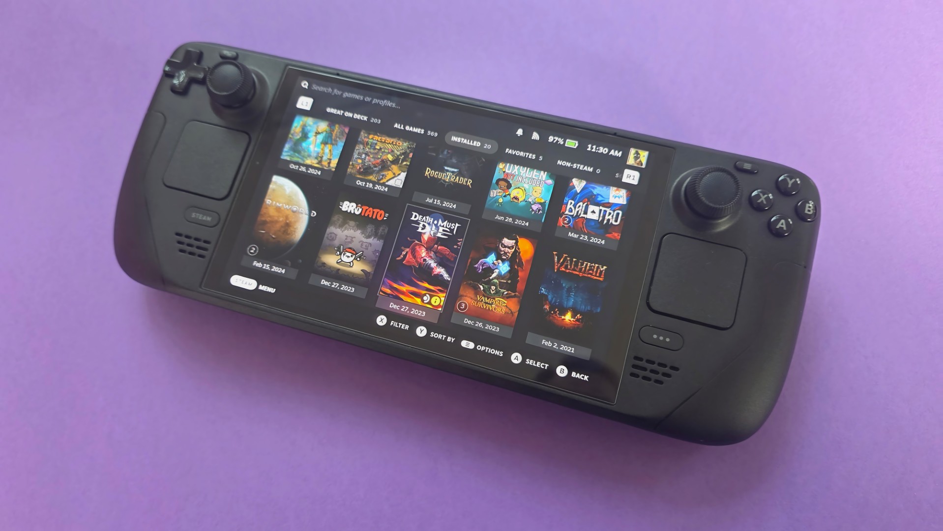 Портативная игровая консоль Steam Deck OLED на фиолетовом фоне.