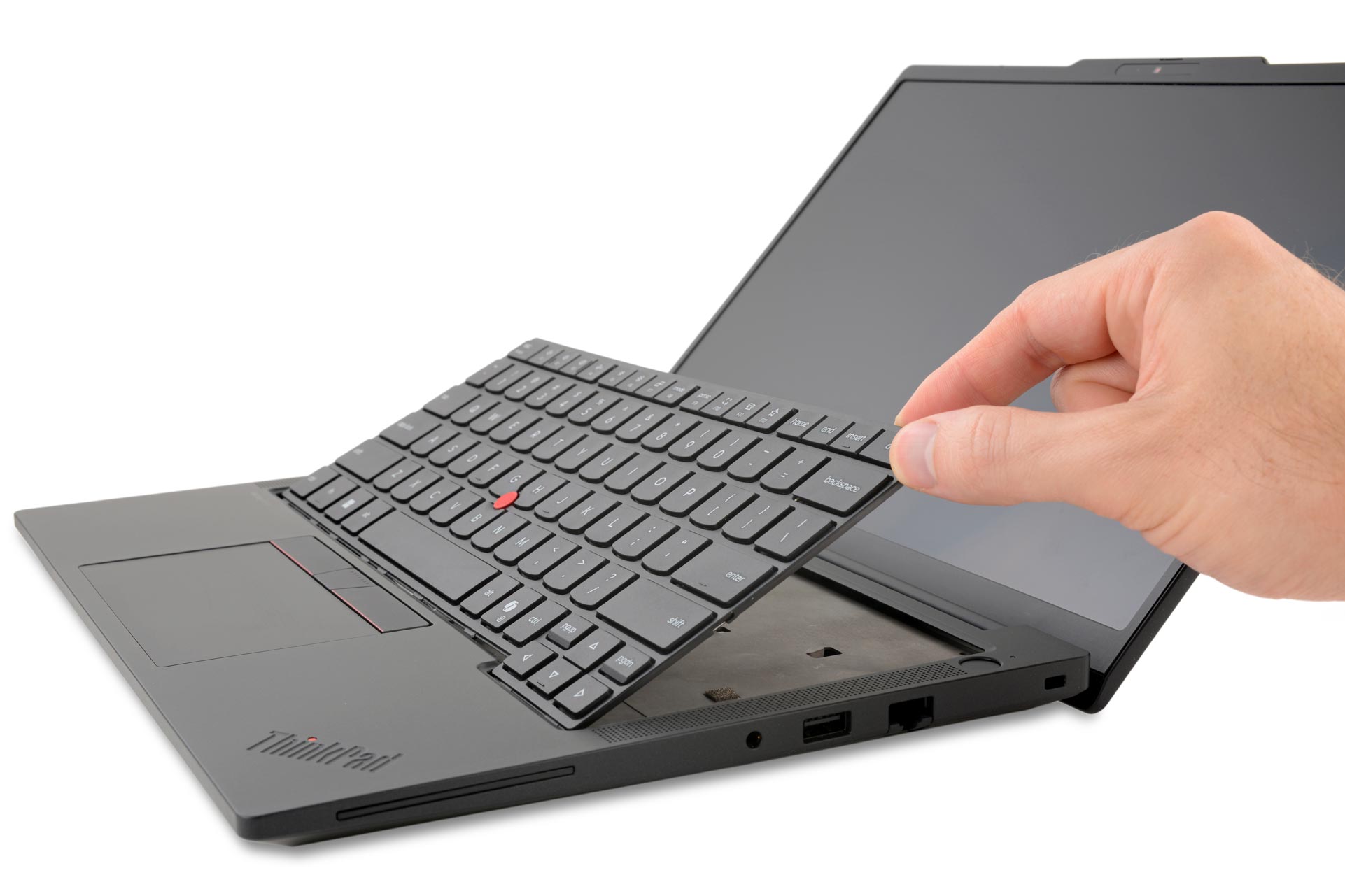 A hand lifts the keyboard from a Lenovo ThinkPad T14 Gen 7 laptop, showing repairable design. The laptop screen is tilted back. The mood is focused, highlighting functionality.