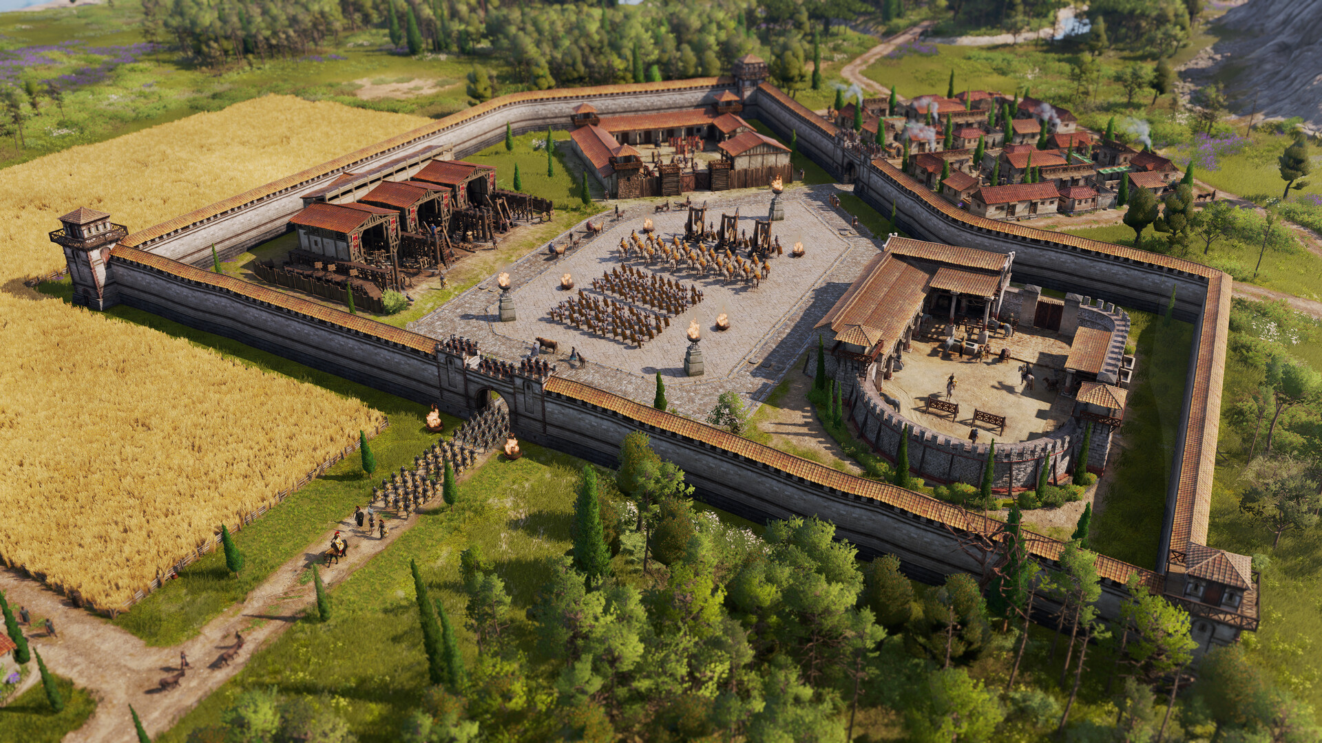 Bird's-eye view of an ancient Roman-style fortress with stone walls, a central courtyard filled with formations of soldiers, surrounded by lush fields and trees.