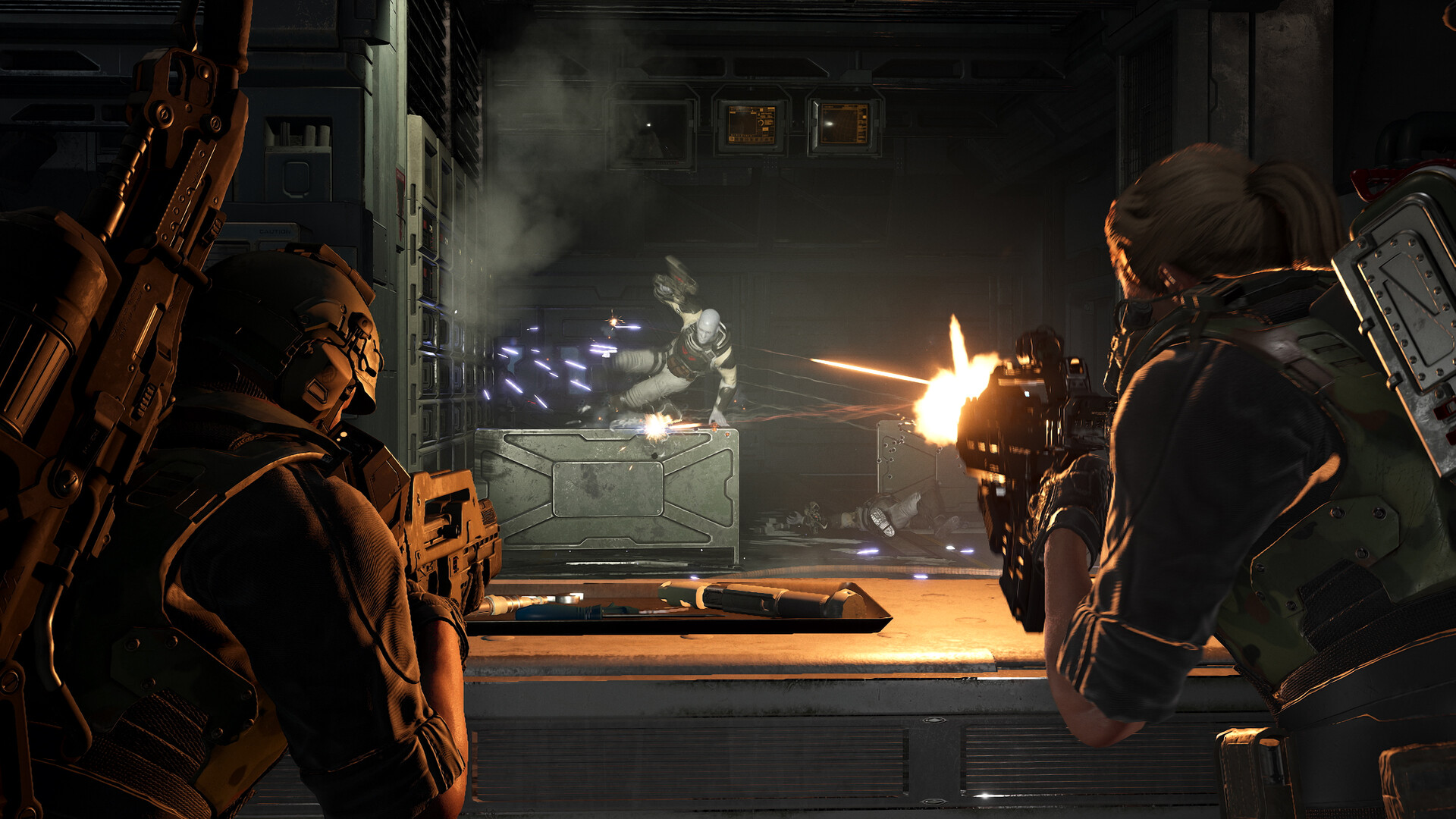 Two futuristic soldiers, one male and one female, fire at an alien creature in a dark, industrial setting. The scene is tense and action-packed.